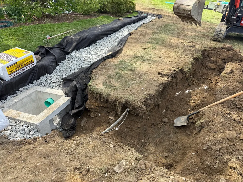 Concrete catch basin and stone drain trench in the yard beside a pool