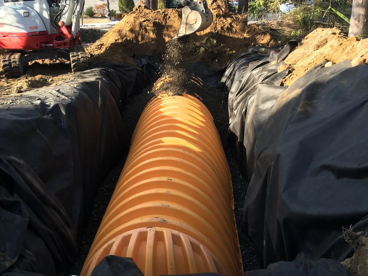 Large corrugated drain pipe set in a lined trench at a home