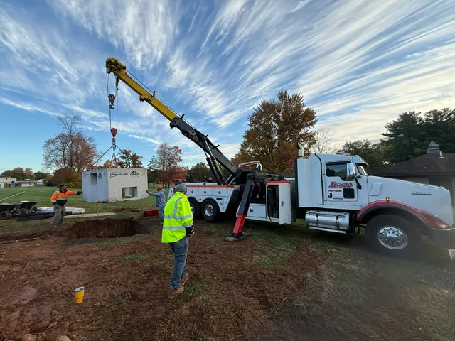 Crane truck setting a precast drainage structure on a field
