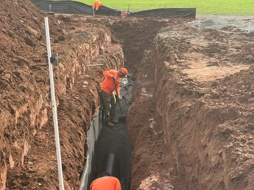 Drain pipe going in along a deep lined trench on a field