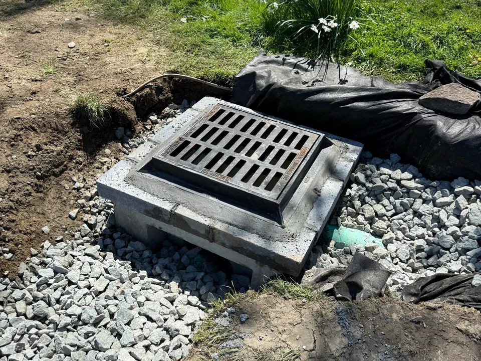 New catch basin grate set in stone at the edge of the yard