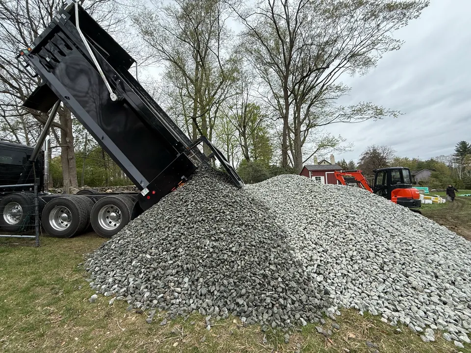 Dump truck unloading drainage stone at a residential job