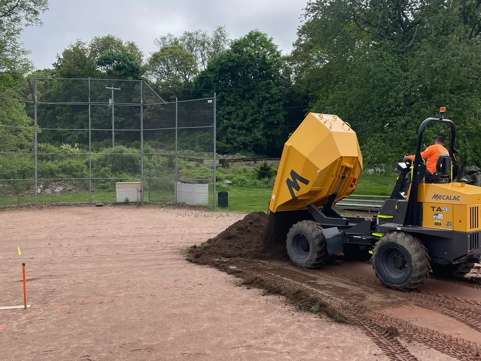 Tracked dumper hauling infield mix onto a ballfield
