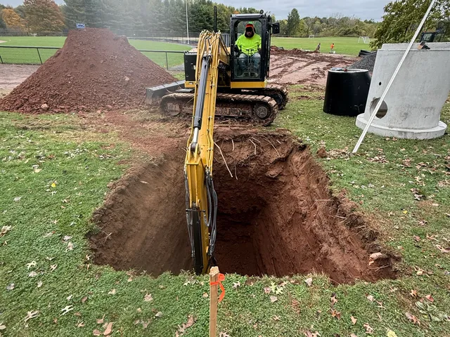 Excavator digging the pit for a catch basin on a field