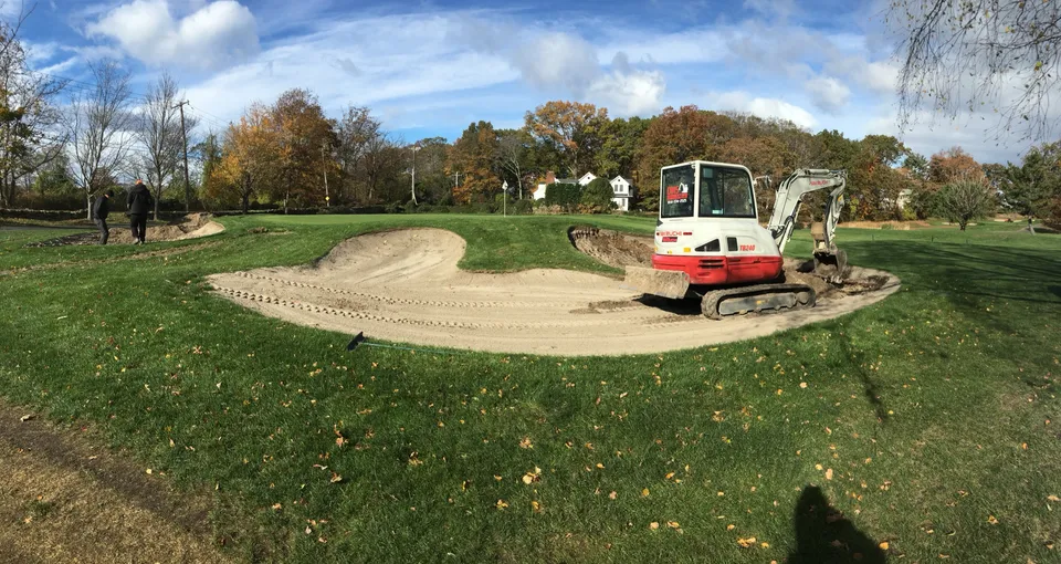 Excavator reshaping a golf course bunker