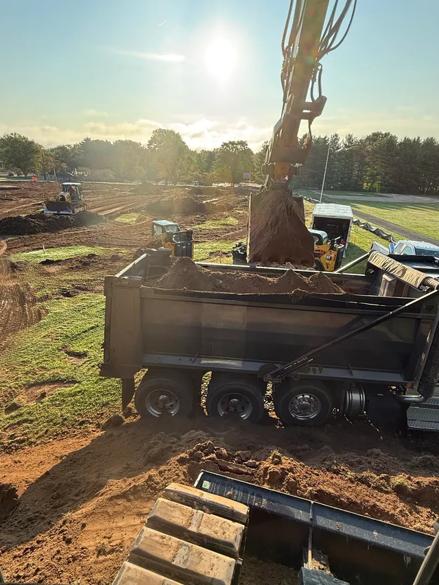 Excavator loading a dump truck at sunrise