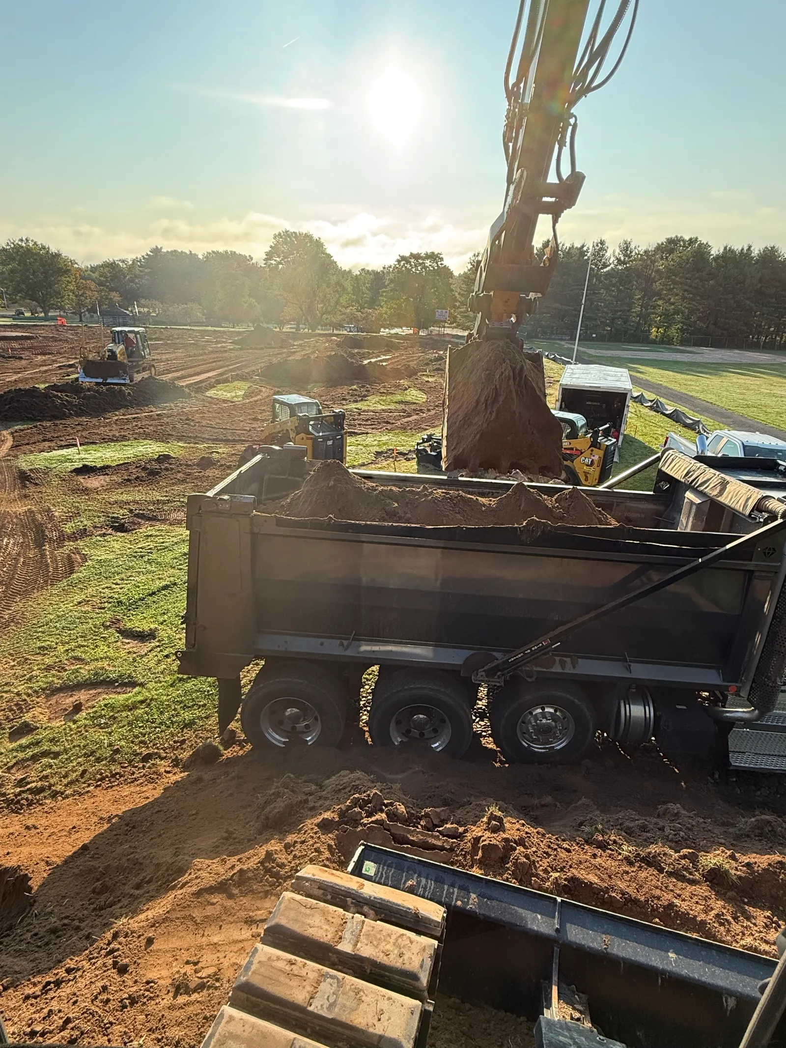 Excavator loading a dump truck at sunrise