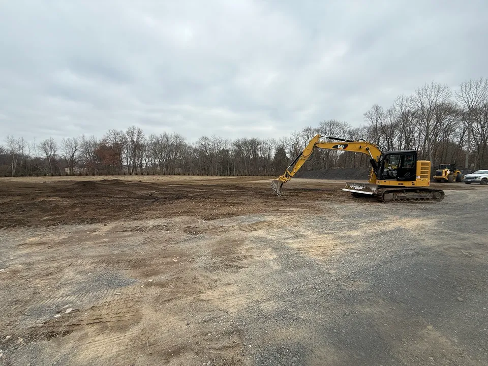 Excavator stripping topsoil on a commercial site