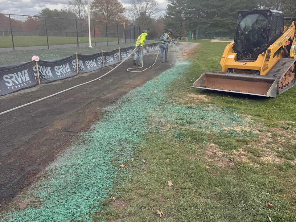 Fresh hydroseed along a ballfield fence line