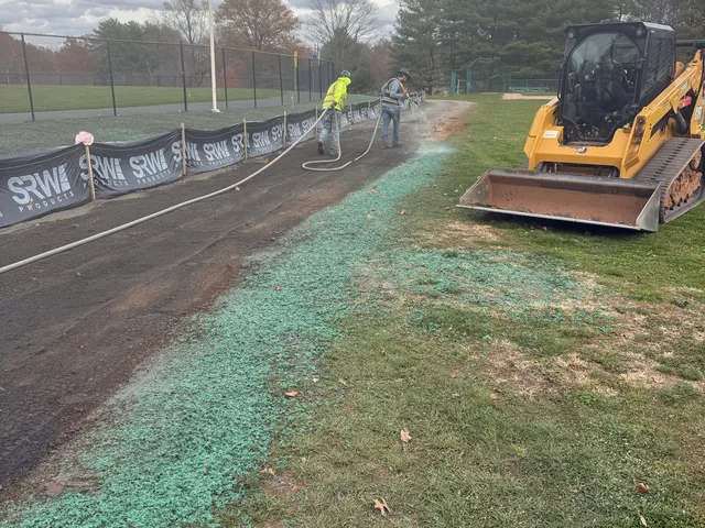 Fresh hydroseed along a ballfield fence line