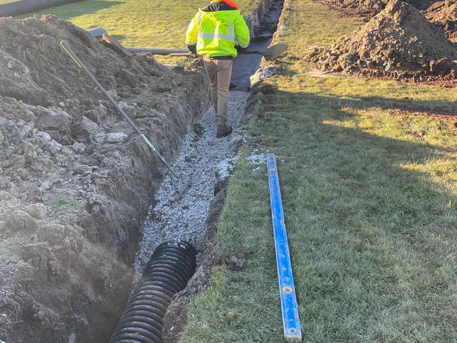 Perforated drain pipe laid in a stone trench in a yard