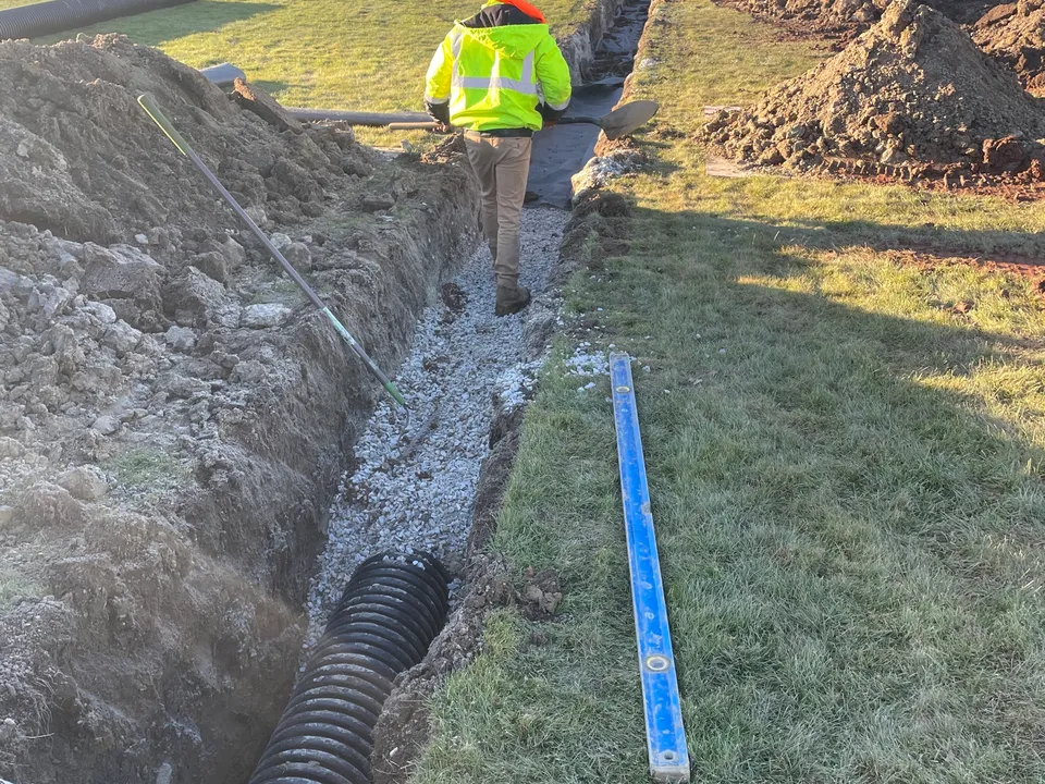Perforated drain pipe laid in a stone trench in a yard