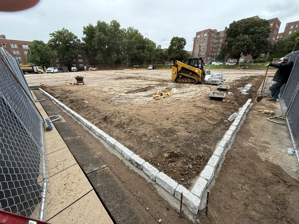 Skid steer grading beside a new granite curb line