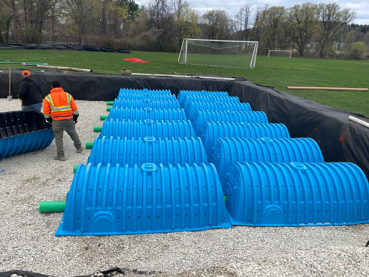 Underground stormwater chambers being set in a stone bed beside a soccer field