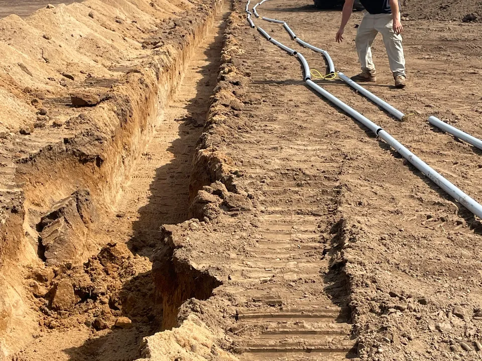 Drain pipe going into a field trench ahead of the excavator
