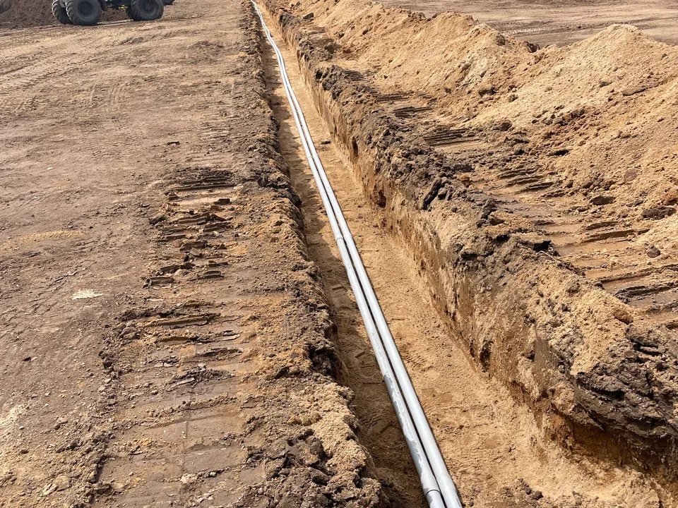 Long drain pipe run in an open trench across a field