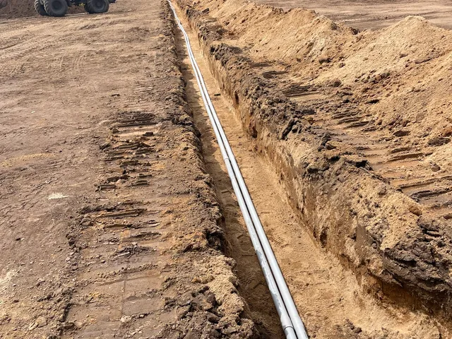 Long drain pipe run in an open trench across a field